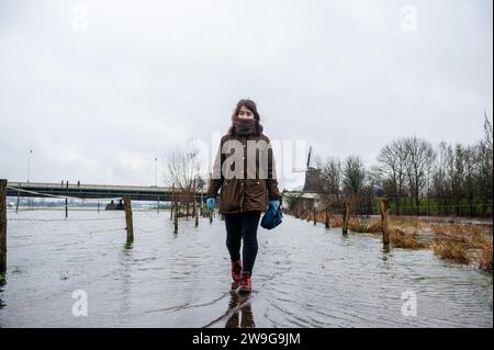 Deventer, Niederlande. Dezember 2023. Eine Frau wird über eine überflutete Straße laufen gesehen. Aufgrund des steigenden Wassers in der IJssel stellt die Gemeinde Deventer Sandsäcke an den Kai, um die Altstadt zu schützen. Der starke Regen, der in den letzten Monaten gefallen ist, kombiniert mit der Tatsache, dass die Alpen für diese Jahreszeit ungewöhnlich warm sind, hat die IJssel in Overijssel, Gelderland, Drenthe, Brabant und Limburg überschwemmt. (Foto: Ana Fernandez/SOPA Images/SIPA USA) Credit: SIPA USA/Alamy Live News Stockfoto