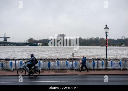 Deventer, Niederlande. Dezember 2023. Menschen werden in der Nähe eines Überschwemmungsgebietes vorbeiziehen gesehen. Aufgrund des steigenden Wassers in der IJssel stellt die Gemeinde Deventer Sandsäcke an den Kai, um die Altstadt zu schützen. Der starke Regen, der in den letzten Monaten gefallen ist, kombiniert mit der Tatsache, dass die Alpen für diese Jahreszeit ungewöhnlich warm sind, hat die IJssel in Overijssel, Gelderland, Drenthe, Brabant und Limburg überschwemmt. Quelle: SOPA Images Limited/Alamy Live News Stockfoto