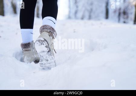 Person mit weißen Schuhen, die am schneebedeckten Wintertag in der Schweiz im Wald spaziert Stockfoto