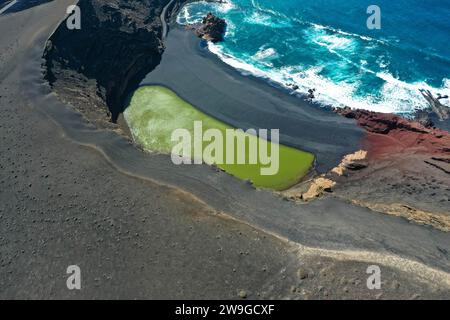 Wunderschöner Blick aus der Vogelperspektive auf El Lago Verde. Grüne Lagune mit Atlantik und schwarzem Sandstrand. Berühmter Aussichtspunkt. Lanzarote, El Golfo, Kanarische Inseln Stockfoto