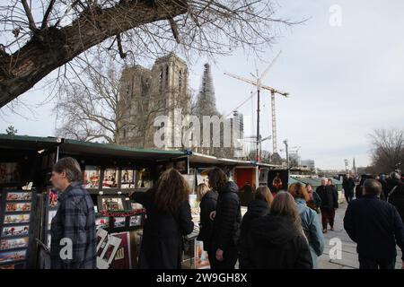 Paris, Frankreich. Dezember 2023. Am 27. Dezember 2023 in Paris, Frankreich, arbeitet man an einem Buchstand am Ufer des Flusses Siene, in der Nähe von Kran am Bau der Kathedrale Notre-Dame im Winter vorbei. Die Arbeiter der Kathedrale Notre-Dame stützen das zerbrechliche Gebäude nach einem verheerenden Brand im 15. April 2019 weiter. (Foto von Paulo Amorim/SIPA USA) Credit: SIPA USA/Alamy Live News Stockfoto