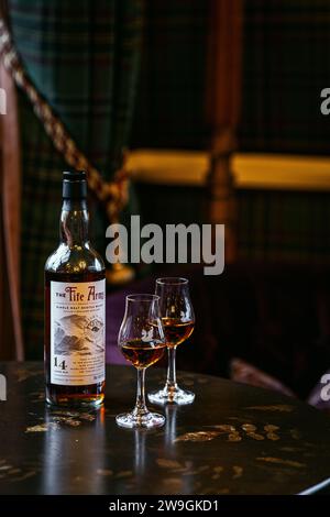 Single Malt Whisky Flasche mit zwei Gläsern auf dem Tisch mit Wohnzimmer im Hintergrund. Stockfoto