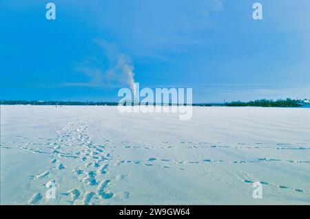 Ein altes Kohlekraftwerk Emission von giftigem Rauch in die Atmosphäre, industrielle urbane Winterlandschaft mit gefrorenem Fluss Stockfoto