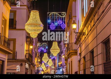 Sevilla, Spanien - 16. Dezember 2023: Weihnachtsbeleuchtung in der Sierpes Street in Form eines goldenen Kristallleuchters im Empire-Stil in Sevilla Stockfoto