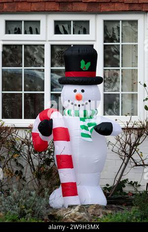Schneemann Weihnachten saisonale aufblasbare Outdoor-Dekoration mit rotem und weißem Zuckerrohr-Oberhut grünem und weißem Schal und Fenstern im Hintergrund Stockfoto