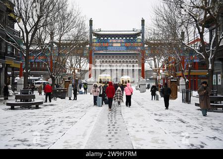 (231228) -- PEKING, 28. Dezember 2023 (Xinhua) -- Menschen besuchen die Qianmen-Straße vor dem Pfeilturm des Zhengyang-Tors bei Schneefall in Peking, Hauptstadt Chinas, 14. Dezember 2023. Die Pekinger Zentralachse, kurz Zhongzhouxian, wurde in der Yuan-Dynastie (1271–1368) gegründet und erstreckt sich 7,8 Kilometer zwischen dem Yongding-Tor im Süden der Stadt und dem Trommelturm und Glockenturm im Norden. Die meisten großen Altstadtgebäude Pekings befinden sich entlang dieser Achse. Tore, Paläste, Tempel, Plätze und Gärten der Altstadt sind alle mit der Achse verbunden. Als sie Zeugen der volkstümlichen Aktivitäten waren Stockfoto