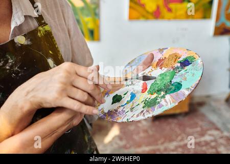 Zugeschnittene Ansicht von reifer Frau und geschickter Frau, die Farben auf Palette mischen, Meisterklasse im Kunststudio Stockfoto