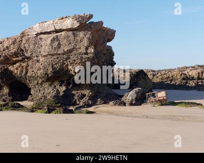 Großer Felsen an einem Sandstrand mit einem Handwagen in Essaouira, Marokko. Dezember 2023 Stockfoto