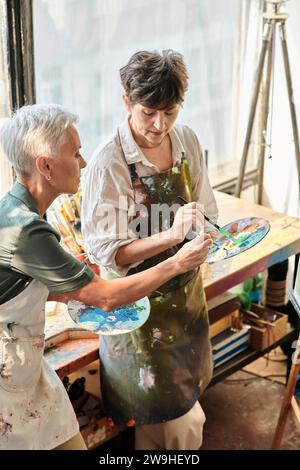 Reife Künstlerinnen mischen während des Meisterkurses im Kunststudio Farben auf der Palette, kreatives Hobby Stockfoto