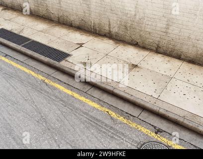 Ein Abschnitt einer abgenutzten und schmuddeligen leeren Straße, gepflasterter Bürgersteig und schwarze Ziegelwand – 3D-Rendering Stockfoto