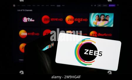 Person, die ein Smartphone mit dem Logo der indischen Videostreaming-Plattform ZEE5 vor der Website hält. Schwerpunkt auf dem Display des Telefons. Stockfoto