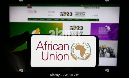 Person mit Smartphone und Logo der kontinentalen Organisation Afrikanische Union (AU) vor der Website. Schwerpunkt auf dem Display des Telefons. Stockfoto