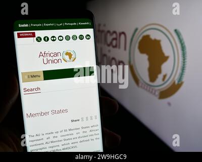 Person, die ein Mobiltelefon hält und die Website der kontinentalen Organisation Afrikanische Union (AU) vor dem Logo zeigt. Konzentrieren Sie sich auf die Mitte des Telefondisplays. Stockfoto