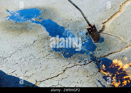 Bitumenemulsionsfugendichtungsrestaurier wird zur Reparatur von Rissen in Asphaltoberflächen verwendet, indem sie mit flüssiger Fugendichtung gefüllt werden. Stockfoto