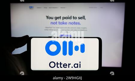 Person, die ein Smartphone mit dem Logo des US-amerikanischen Unternehmens für künstliche Intelligenz Otter.ai Inc. Vor der Website hält. Schwerpunkt auf dem Display des Telefons. Stockfoto