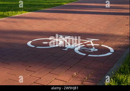 Fahrradweg mit dem Fahrradsymbol auf dem Gehweg im öffentlichen Park der Stadt. Stockfoto