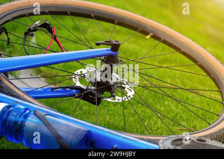 Nahaufnahme eines Vorderrads eines Fahrrads auf dem Rasen. Fahrradbrille in Radspeichen. Aktives Lifestyle-Konzept. Stockfoto