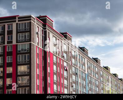 Fassade eines modernen Wohngebäudes. Eckansicht eines Hauses mit farbigen Wänden auf einem Hintergrund von bewölktem Himmel. Stockfoto