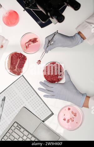 Unerkennbare Wissenschaftlerin bei der Analyse verschiedener Rohfleischsorten im Labor Stockfoto