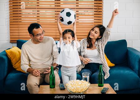 Eine glückliche Familie genießt den Nervenkitzel eines Fußballspiels zu Hause Stockfoto