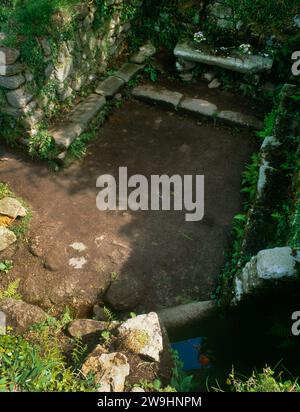 Blick auf den Eingang, die Brunnenkammer (Baptisterium), den Altar und die Bänke in der Madron Chapel, Cornwall, England, Großbritannien: Hauptsächlich auf dem 12. Jahrhundert auf früheren Fundamenten. Stockfoto