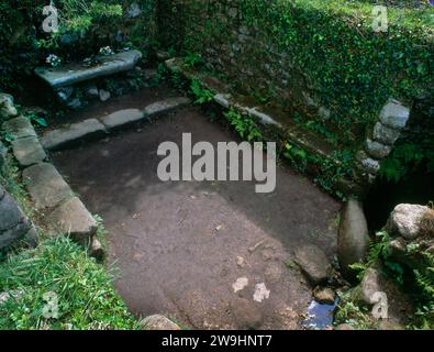 Sehen Sie die Brunnenkammer (Taufhaus auf R), den Altar (hinten L) und die Bänke in der Madron Chapel, Cornwall, England, UK, von der Wand über dem Eingang Stockfoto