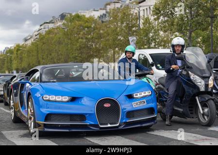 Paris, Frankreich - Atlantic Blue und French Racing Blue Bugatti Chiron fahren auf der Champs Elysée mitten im Verkehr. Stockfoto