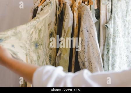 Textilkünstler hält ein Hemd mit Naturblumenfarbe drauf. Umweltfreundlicher botanischer Aufdruck auf der Garderobe für Faserbekleidung. Stockfoto