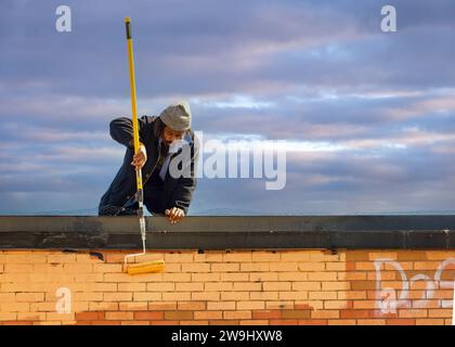 Ein Mann, der ein Graffiti an einer Gebäudewand räumt, Toronto, Kanada Stockfoto