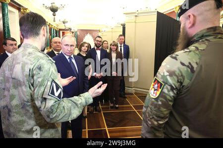 Moskau, Russland. Dezember 2023. Der russische Präsident Wladimir Putin, Zentrum, hört den Mitgliedern des Militärdienstes bei einer Führung durch eine Ausstellung zu den wichtigsten Ereignissen des ausgehenden Jahres der Lehrer und Mentoren im Kreml am 27. Dezember 2023 in Moskau, Russland. Quelle: Gavriil Grigorov/Kreml Pool/Alamy Live News Stockfoto