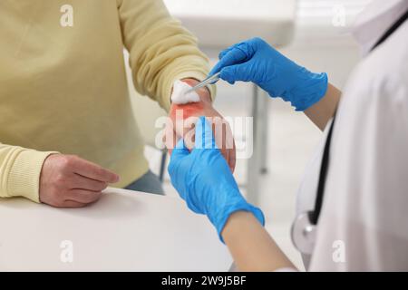 Arzt, der die verbrannte Hand des Patienten im Haus behandelt, Nahaufnahme Stockfoto