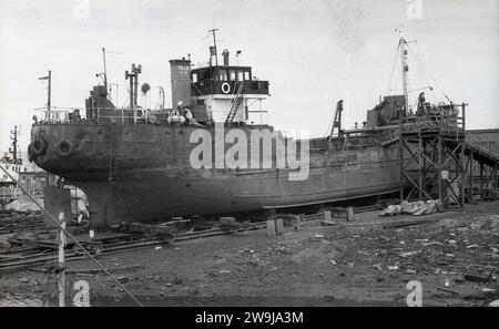 1972, historischer Fischtrawler im Trockendock, der überholt oder wahrscheinlich für Schrott abgebaut wurde, Fleetwood, Lancs, England, Vereinigtes Königreich.die Küstenstadt Fleetwood im Borough of Wyre war einst einer der größten Fischereihäfen des Vereinigten Königreichs mit einer großen Flotte, aber der Niedergang der britischen Fischereiindustrie, der in den frühen 1980er Jahren gemeint war, hatten alle Tiefseetrawler verlassen. Intitials auf Trichter, E S & G. Stockfoto