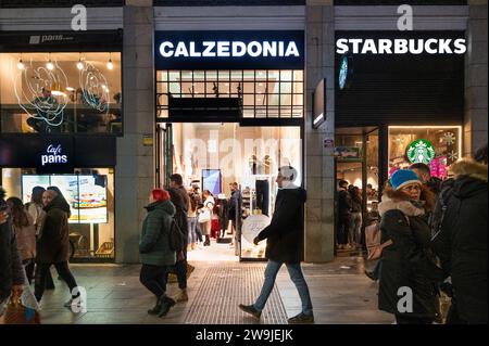 Fußgänger gehen an der italienischen Modemarke Calzedonia und der amerikanischen multinationalen Starbucks-Coffee-Stores in Spanien vorbei. Stockfoto
