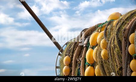 Detail eines Fischernetzes, das auf der Rückseite eines Fischerbootes mit blauem Himmel im Hintergrund gesammelt wurde. Konzept der Fischereiwirtschaft Stockfoto