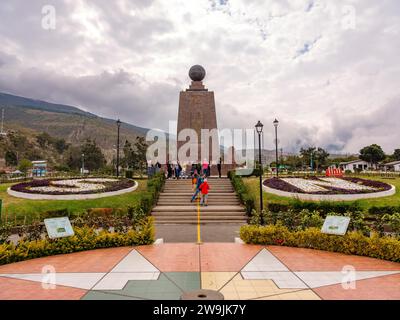 Touristen vor dem Äquatordenkmal Ciudad Mitad del Mundo, dem Zentrum der Welt, Denkmal mit Globus und gemalter Linie, die den Äquator markiert Stockfoto