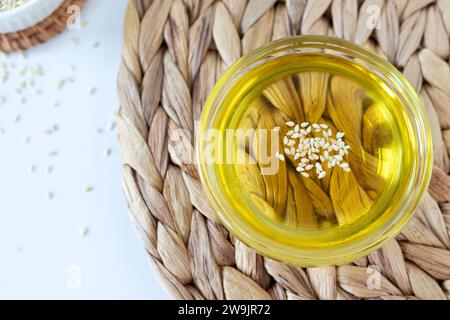 Sesamöl mit Samen in Glasschale auf rustikalem Hintergrund. Draufsicht, Nahaufnahme. Stockfoto