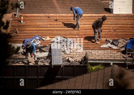 In Vorbereitung auf den Dachaustausch entfernen hispanische Arbeiter alte Schindeln in Laguna Niguel, CA. Stockfoto