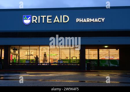 Issaquah, WA, USA - 10. Dezember 2023; Nachtansicht der Rite Aid Apotheke mit Lichtern im Schaufenster und Reflexion in nassem Asphalt Stockfoto