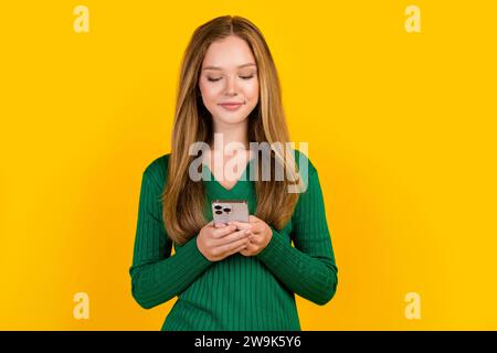 Foto-Porträt eines fokussierten Teenagersüchtigen Mädchens, das Videos auf youtube-Trendinhalten mit Telefon auf gelbem Hintergrund surft Stockfoto