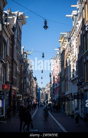 AMSTERDAM - 24. Oktober 2021: Blick auf Menschen, die in einer engen Straße in Amsterdam spazieren gehen. Historische, traditionelle und typische Gebäude und viele Pflanzen sind in Stockfoto