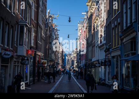 AMSTERDAM - 24. Oktober 2021: Blick auf Menschen, die in einer engen Straße in Amsterdam spazieren gehen. Historische, traditionelle und typische Gebäude und viele Pflanzen sind in Stockfoto