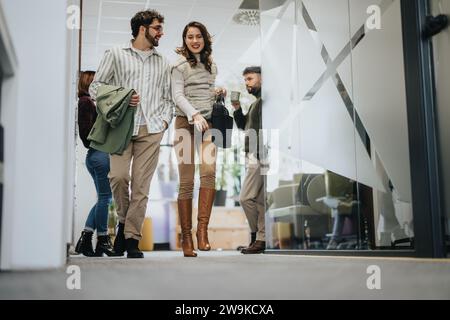 Junge Mitarbeiter diskutieren und lächeln, wenn sie das Büro nach der Arbeitszeit verlassen. Stockfoto