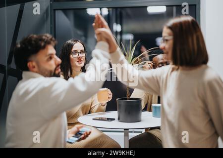 Junge, multirassische Kollegen, die zusammen eine Pause machen. Sie genießen die gemeinsame Nachtarbeit in positiver Atmosphäre. Die Leute geben einander High-Five Stockfoto