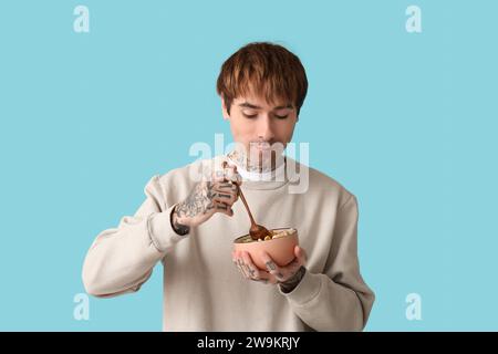 Mann hält Schüssel mit Müsliringen und Löffel auf blauem Hintergrund Stockfoto