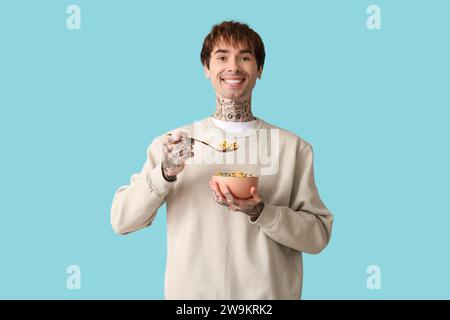 Mann hält Schüssel mit Müsliringen und Löffel auf blauem Hintergrund Stockfoto