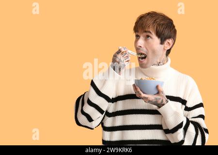 Mann isst Getreideringe auf gelbem Hintergrund Stockfoto
