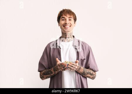 Mann, der eine Schüssel mit Müsliringen auf weißem, strukturiertem Hintergrund hält Stockfoto