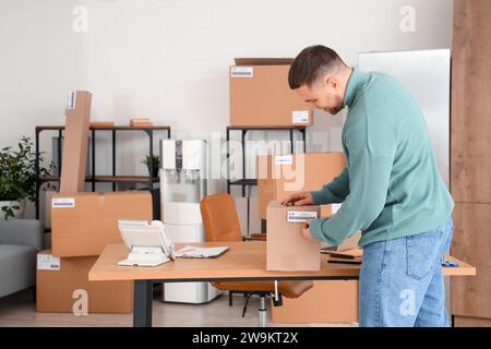 Männlicher Verkäufer, der das Paket für den Kunden im Lagerhaus verpackt Stockfoto