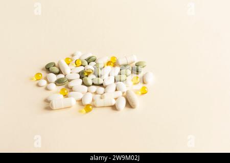 Gemischter Stapel von bunten Pillen, Grün weiß Gelb, Beige Tabletten, Kapseln, medizinische Ergänzung auf Beige Hintergrund. Pharmazeutisches Konzept. Kopieren Stockfoto