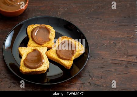 Toast mit Dulce de leche auf einem schwarzen Teller, typisch argentinischer Snack. Stockfoto